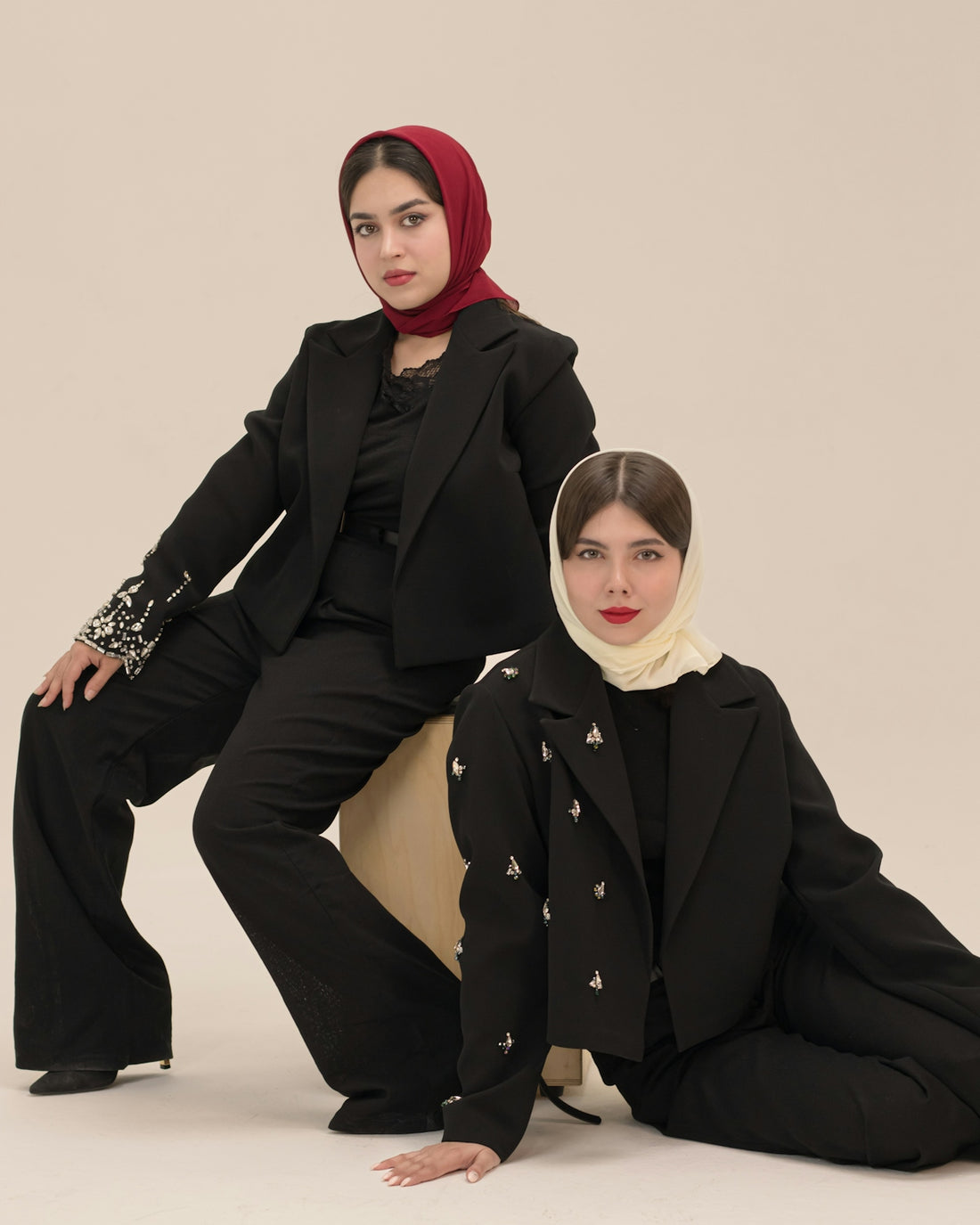 Two women in stylish black suits and hijabs.