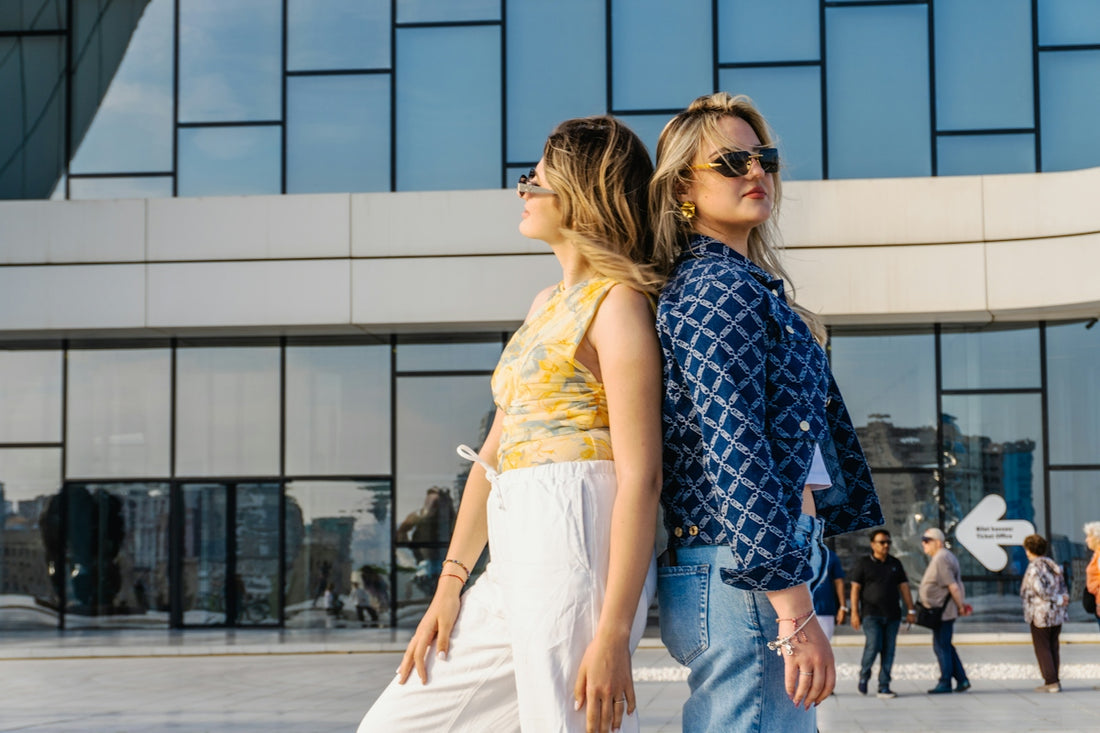 Two women stand back to back outdoors