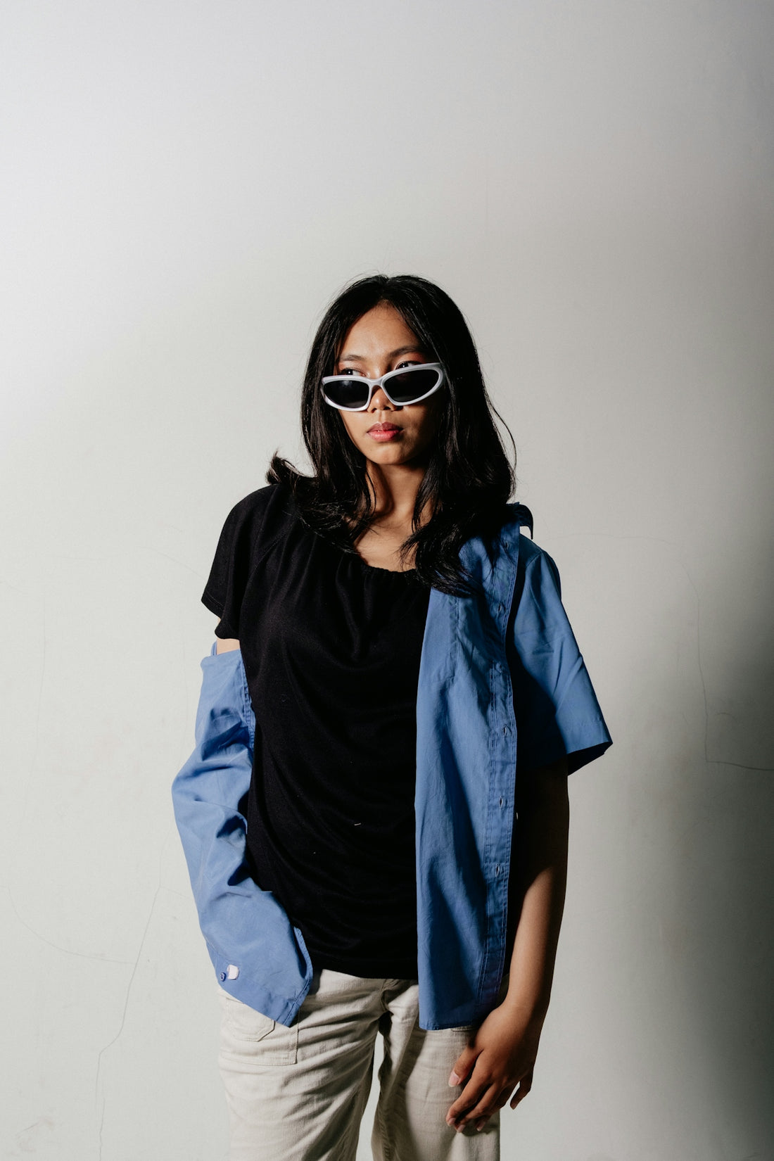 Young woman wearing sunglasses, black t-shirt, and blue shirt.