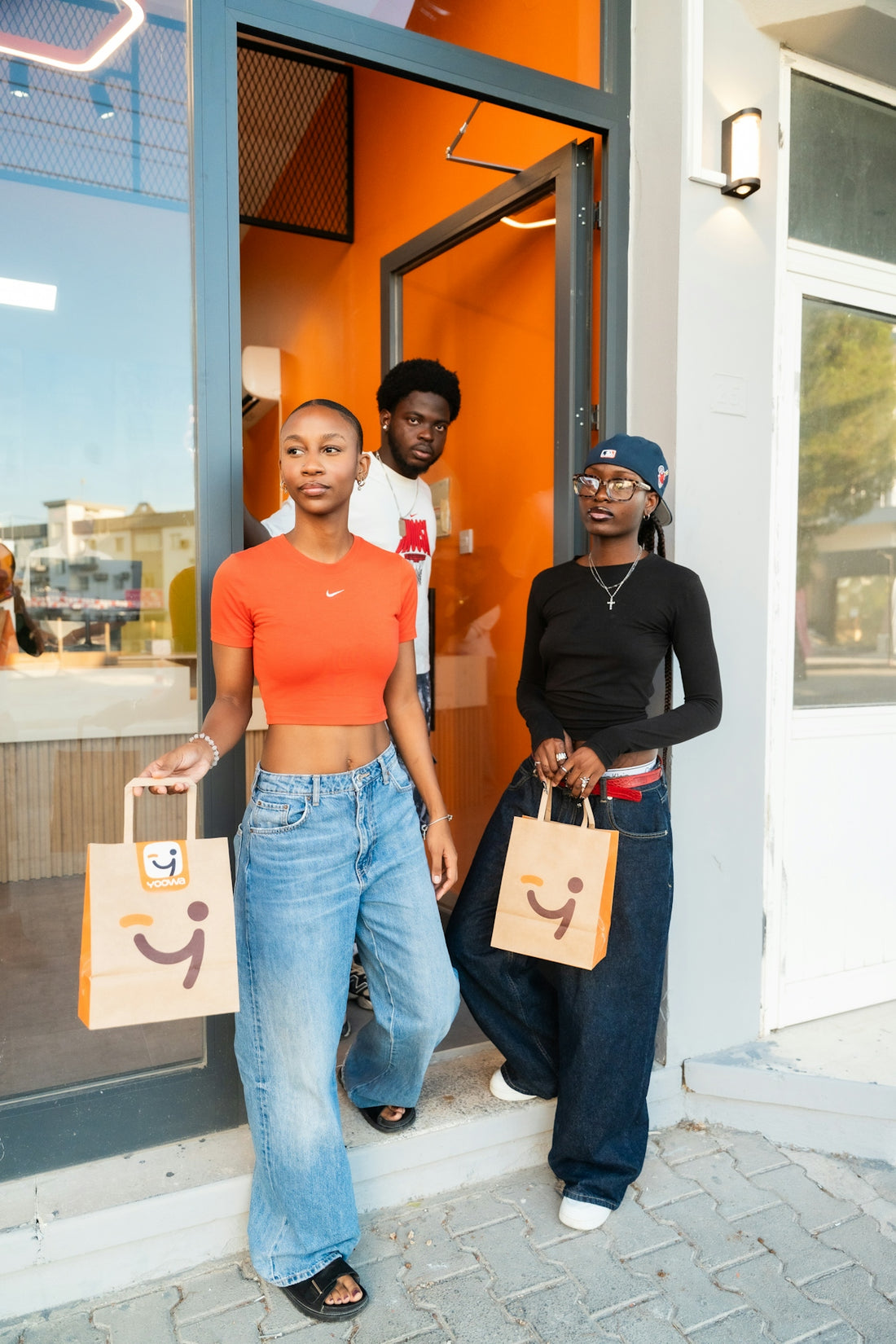Three young people exiting a store with shopping bags.